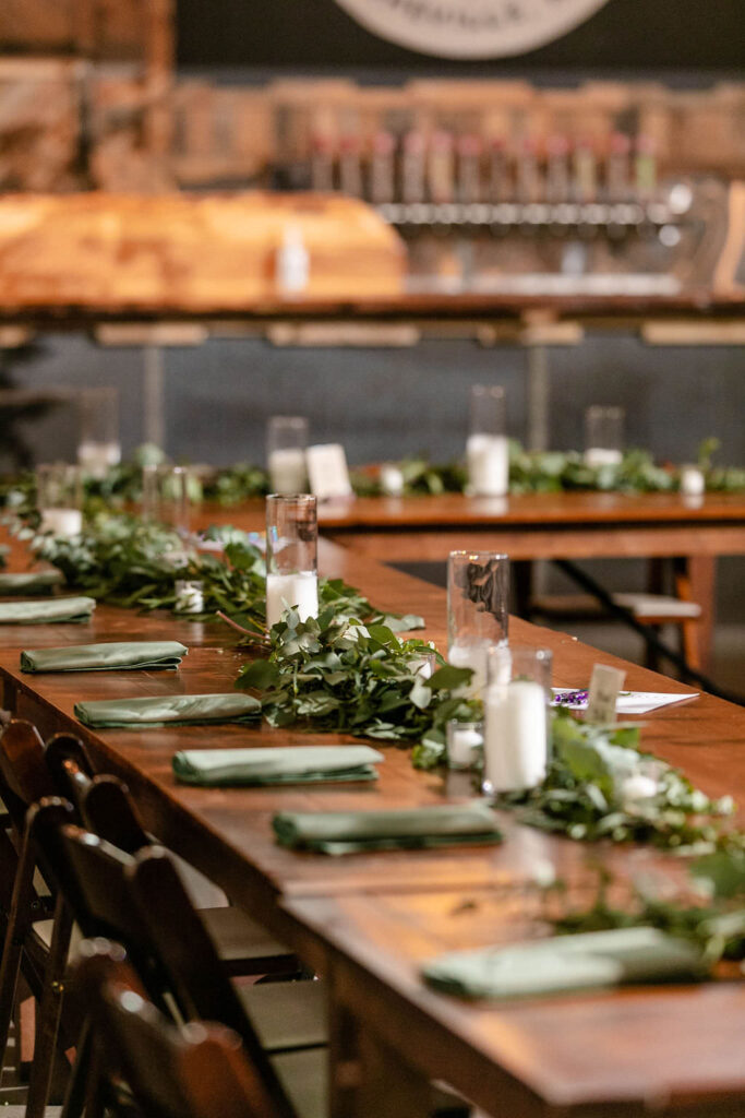 Candles and greenery lining wedding reception tables. 