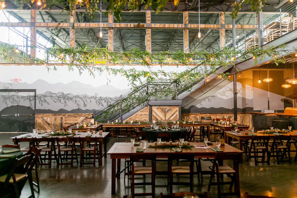 A reception hall set up for a wedding reception with a mountain scape mural painted on the wall 