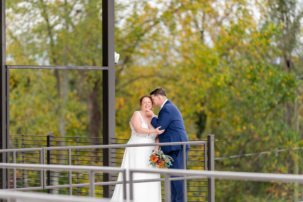 A groom with his head on his brides as they both smile 