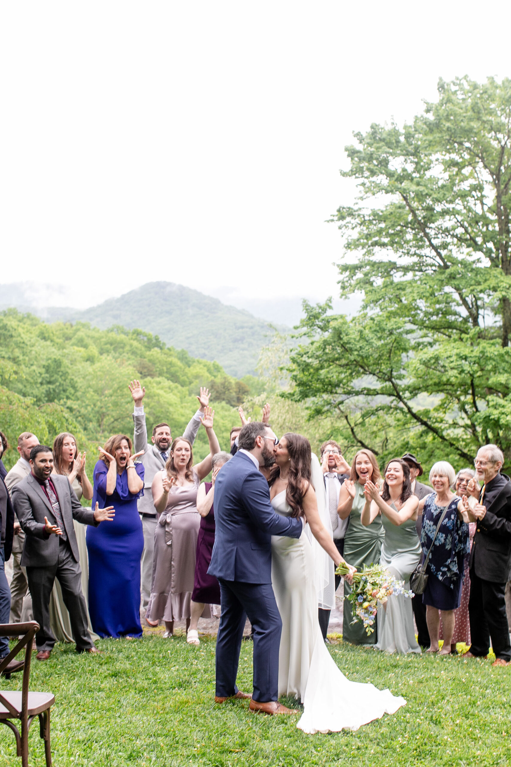 bride and groom kissing with guests cheering behind them