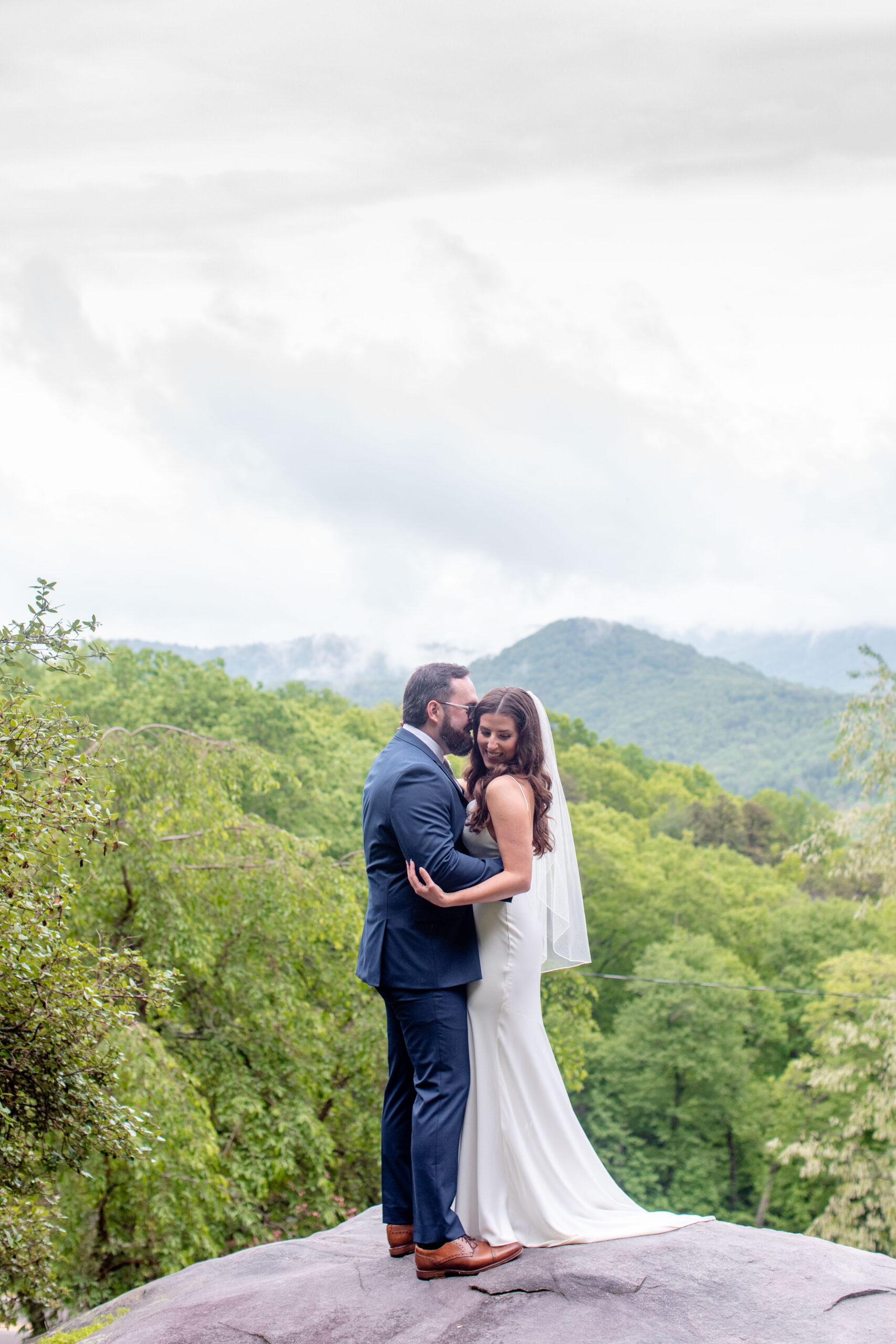 bride and groom standing on rock with mountains behind them