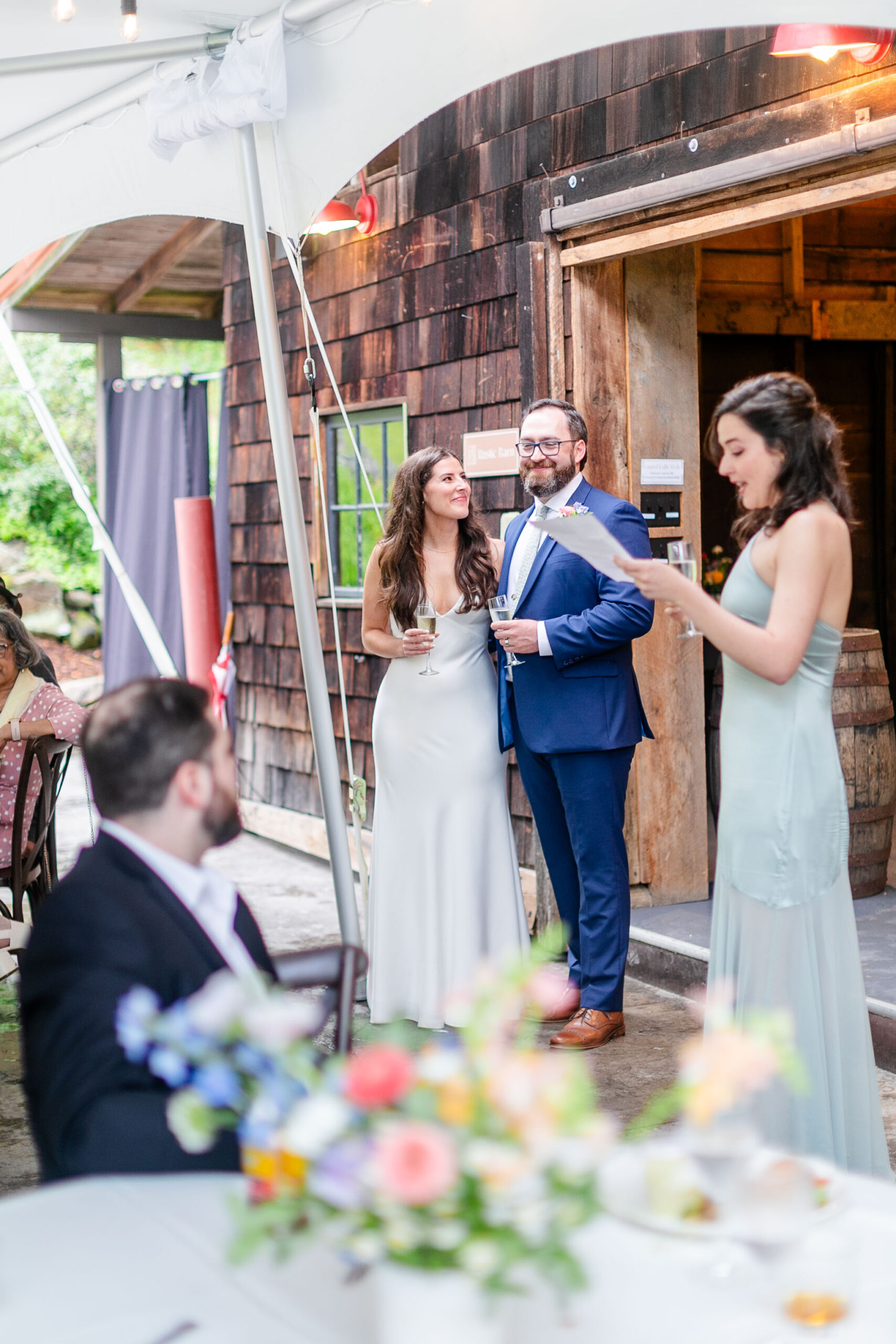 bridesmaid giving speech with bride and groom in the background