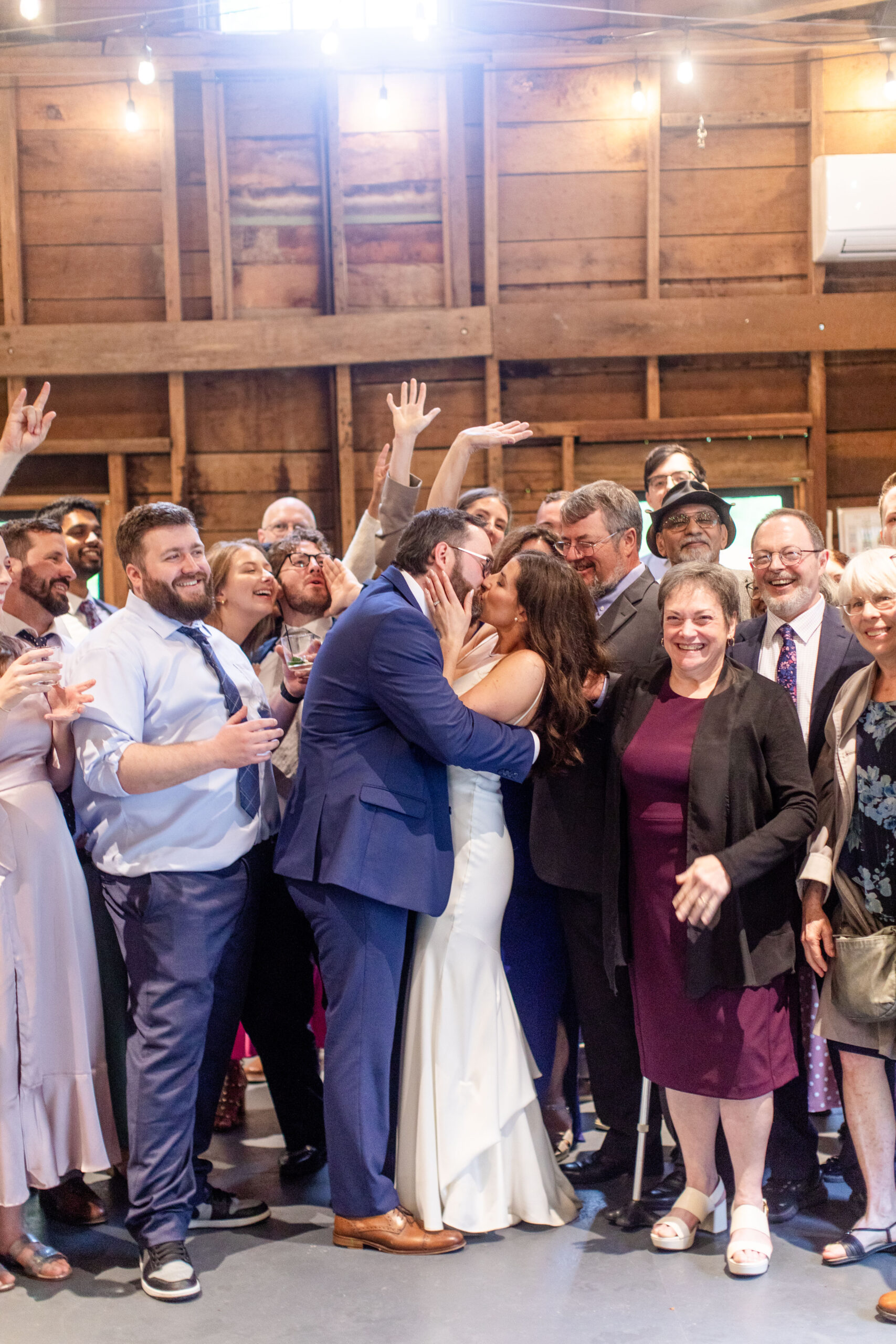 bride and groom kissing with guests behind them cheering