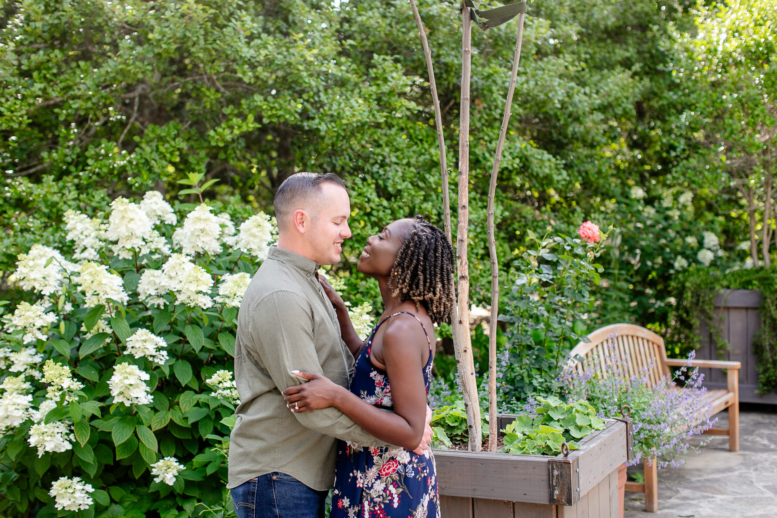 a man and a woman looking at each other and smiling surrounded by flora and fauna 