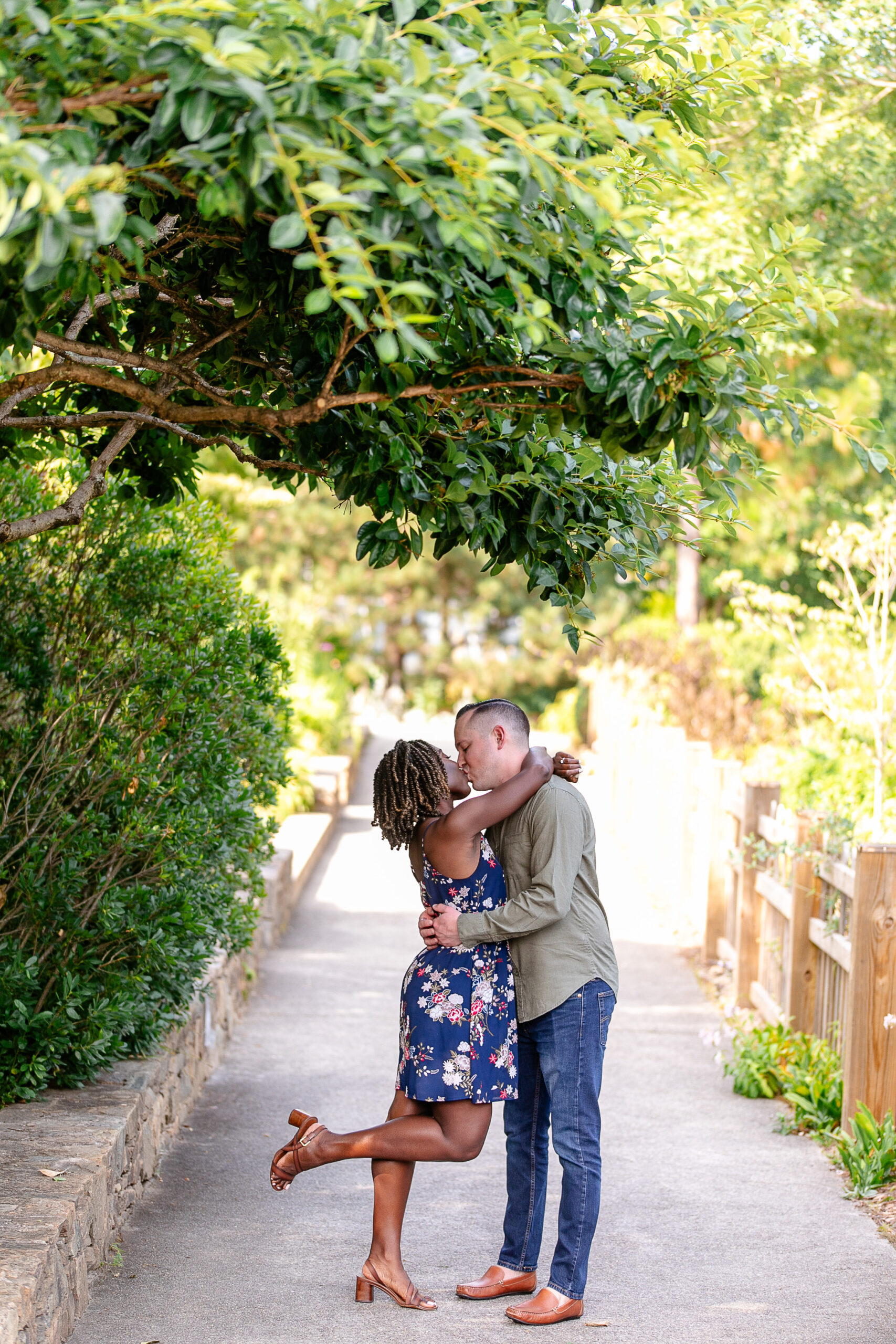 a man and a woman giving each other a kiss underneath of a tree 