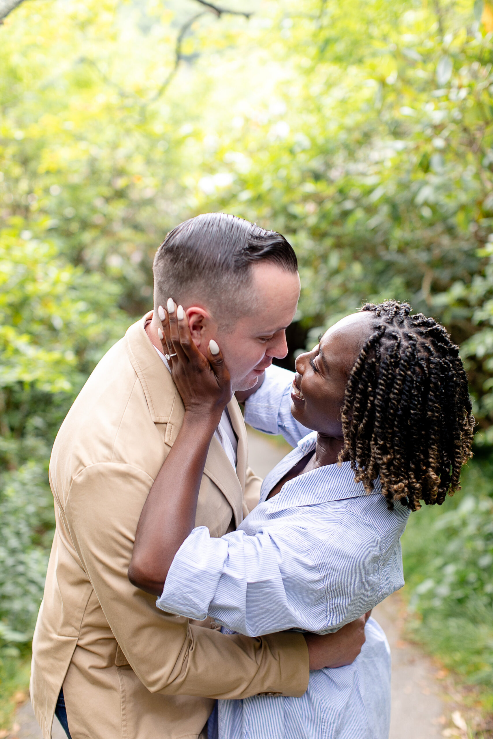 the woman has her hands on the side of the man's face and both the man and woman are looking at each other and smiling 