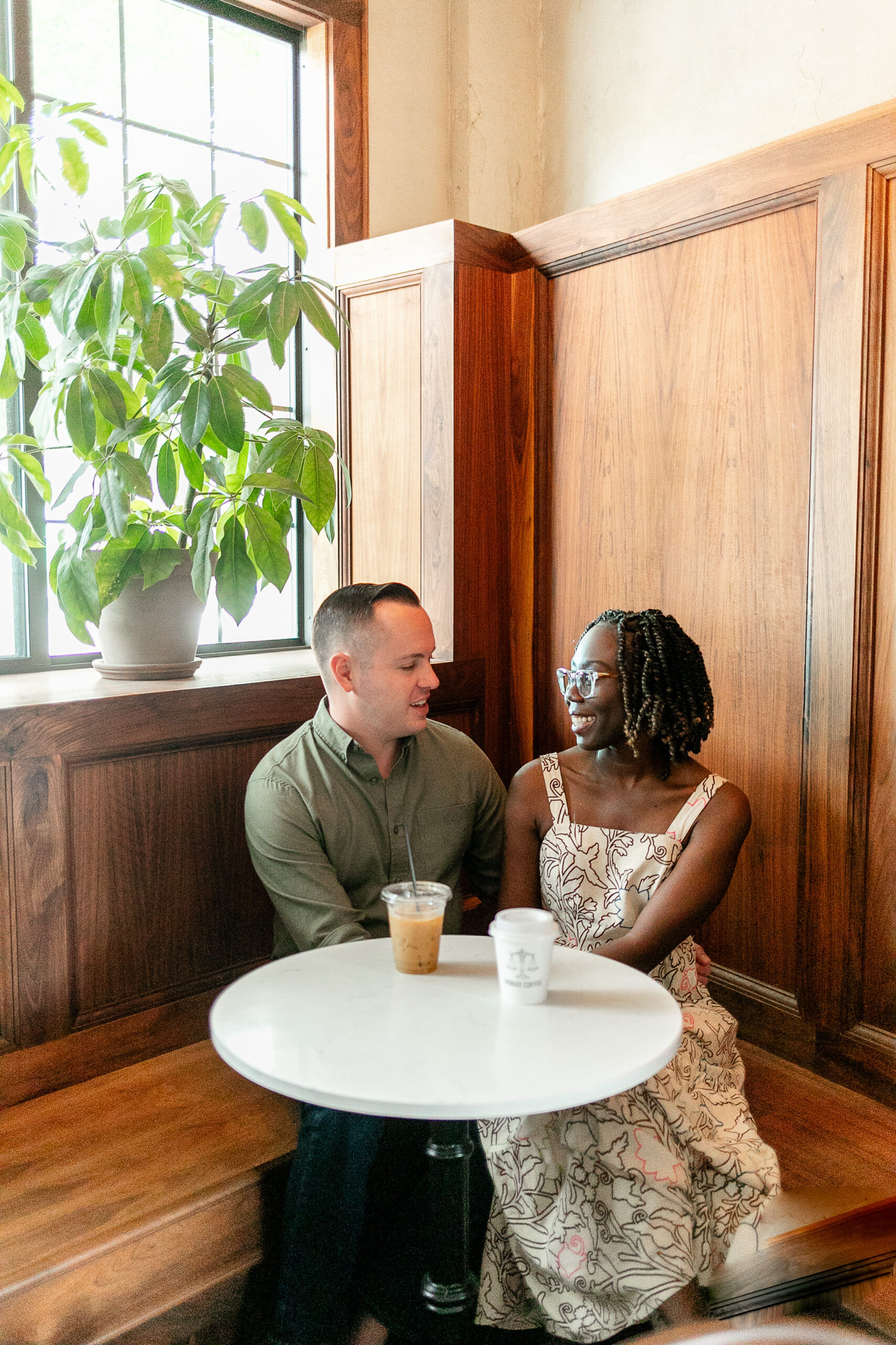 a man and a woman in a coffee shop sitting next to each other and looking at each other