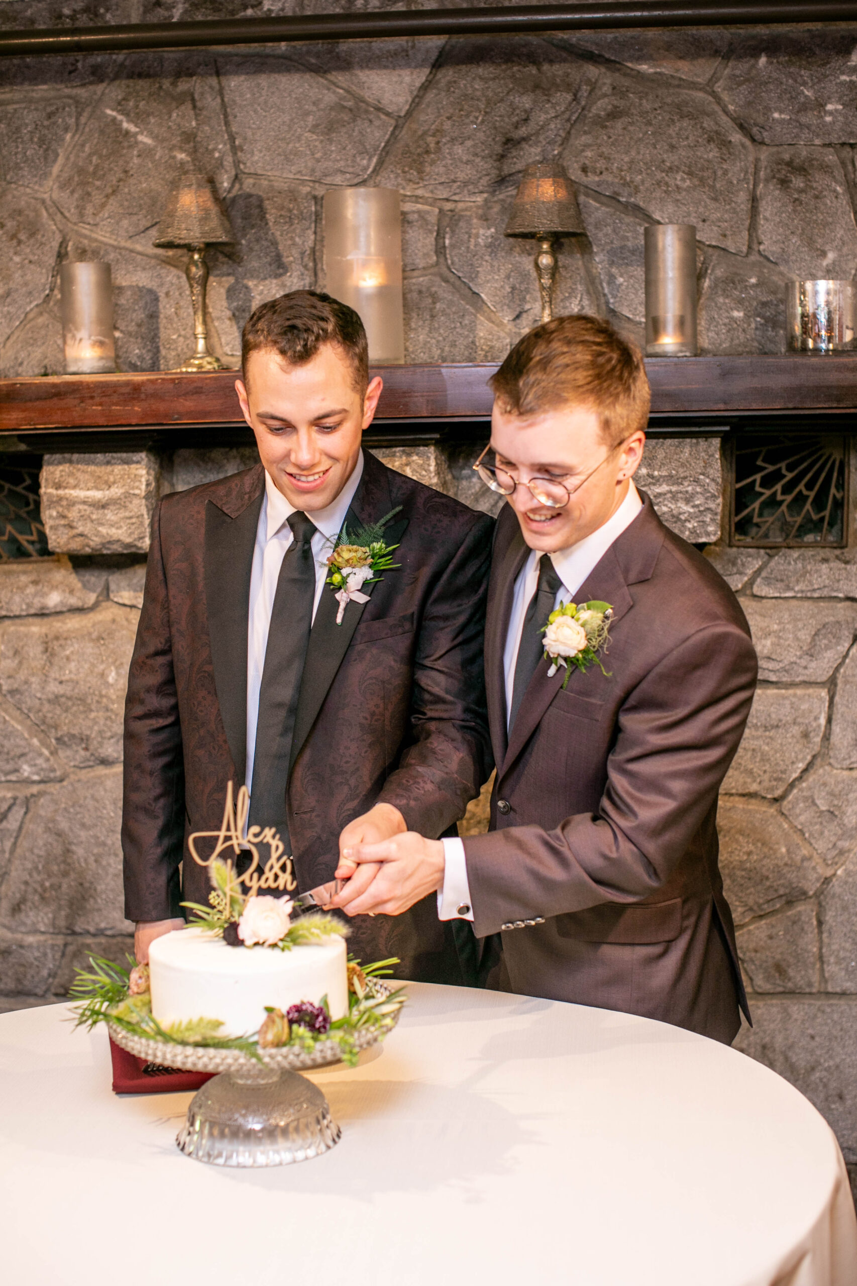 two men in suits who just got married cutting their wedding cake 