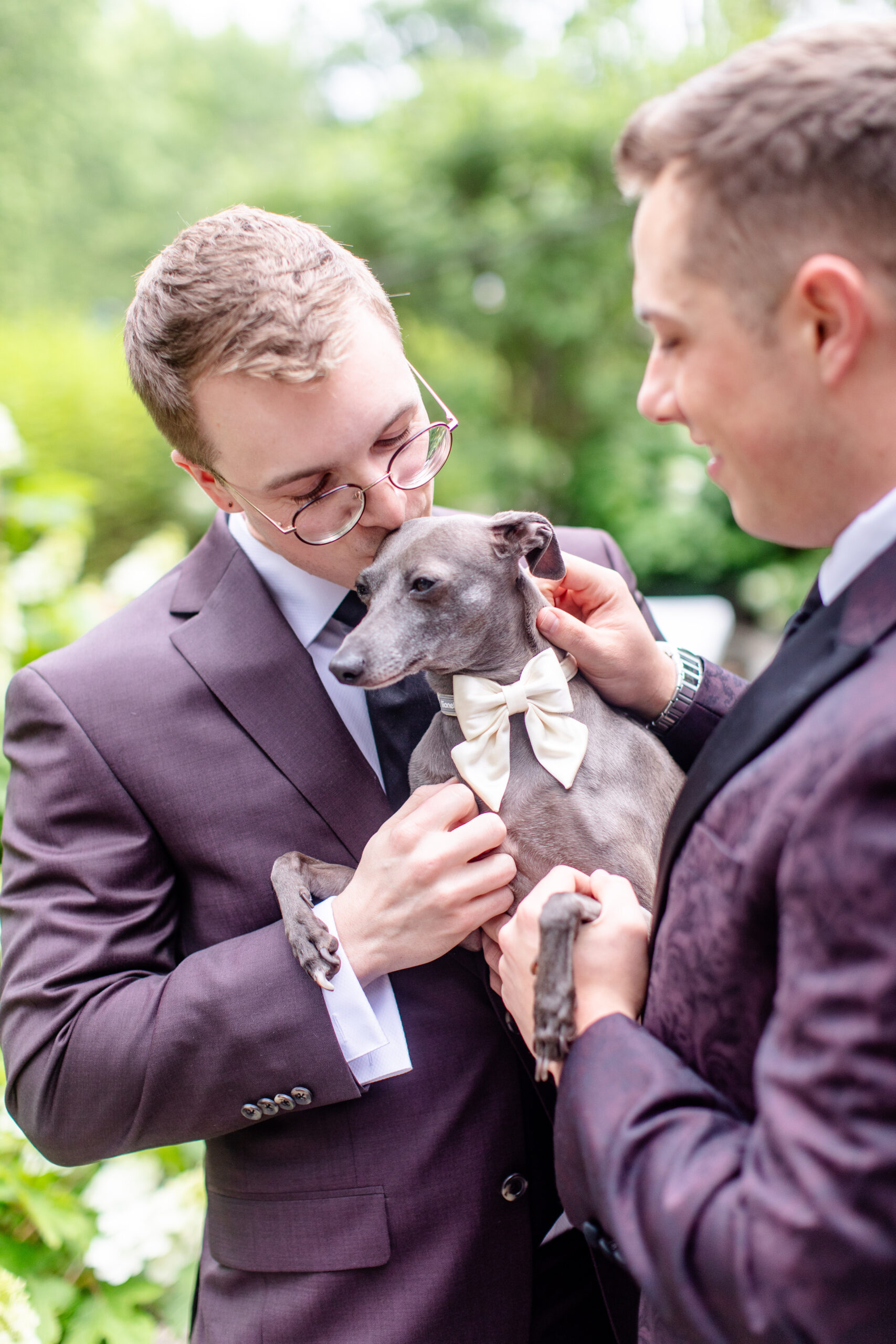 two men in suits holding a dog 