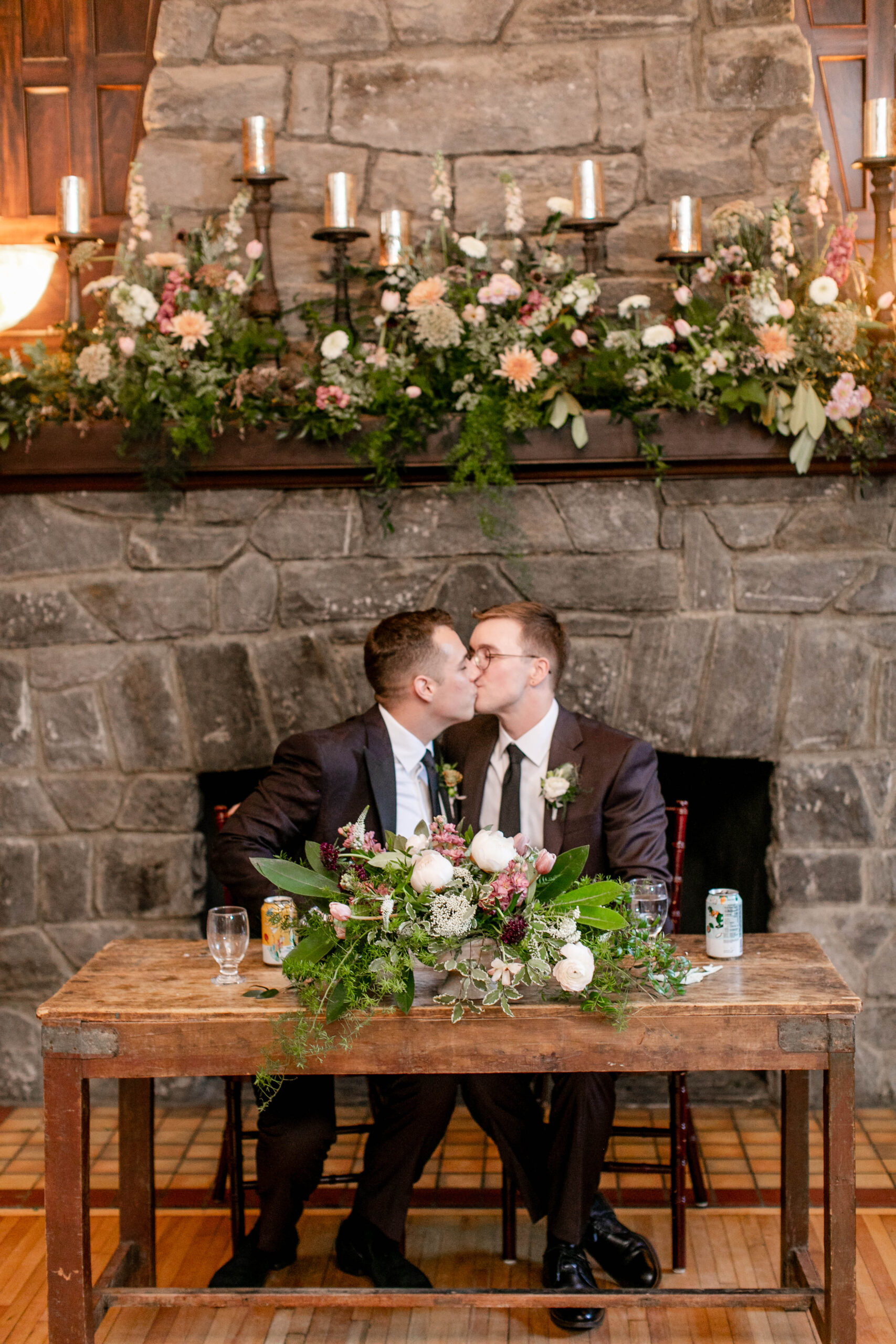 two men who just got married giving each other a kiss in front of a stone fireplace 