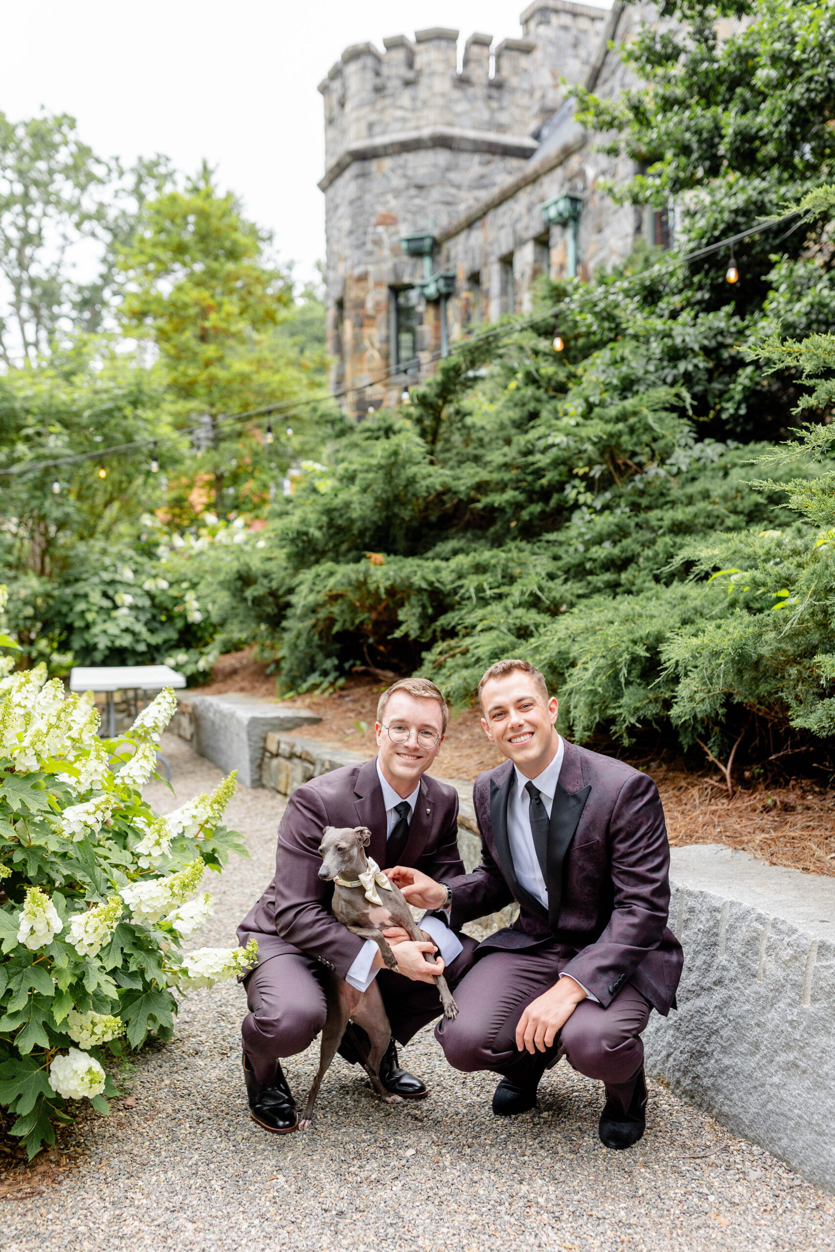 two men in suits holding a dog