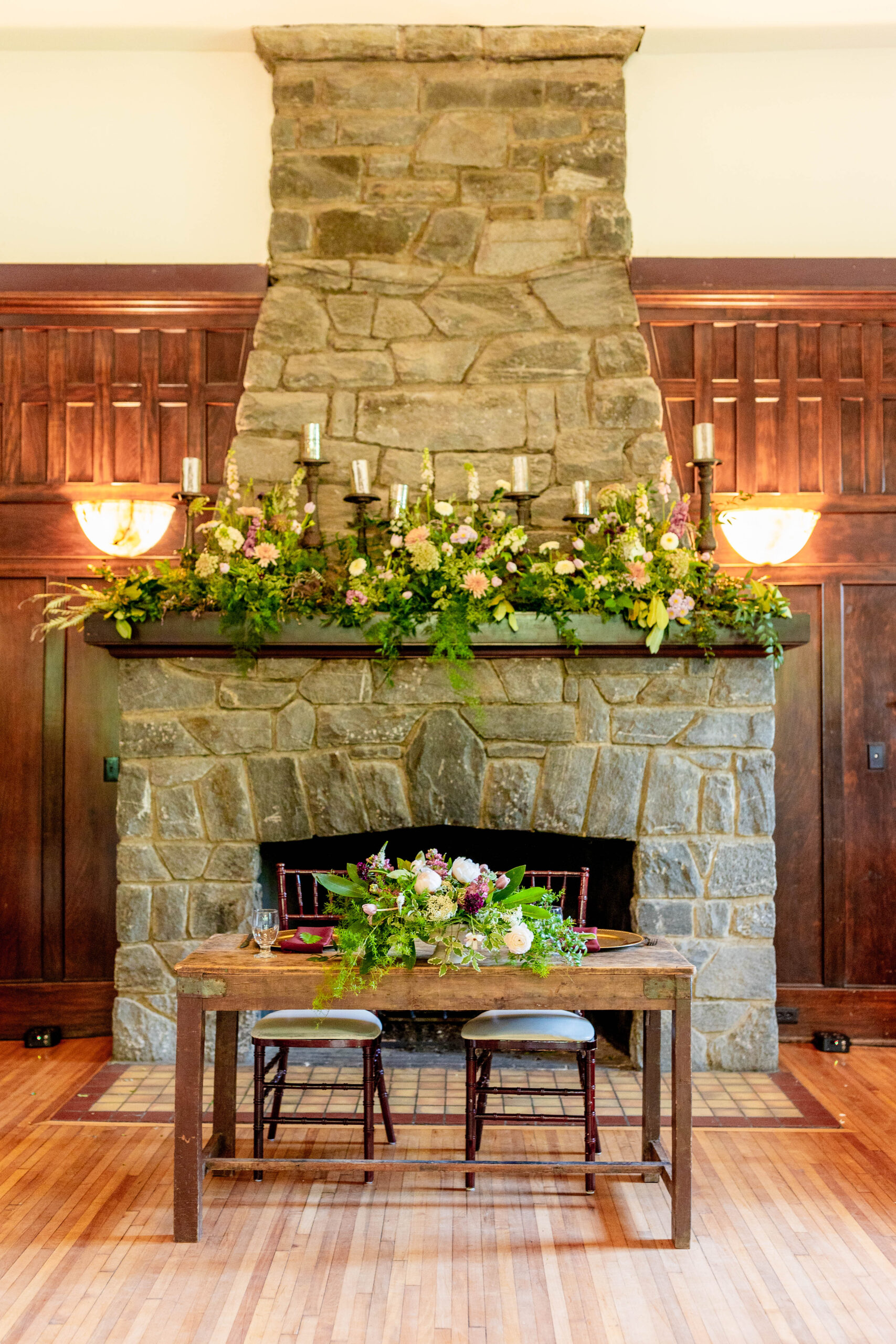 stone fireplace with two lamps and a table with flowers at the Homewood wedding venue in Asheville 