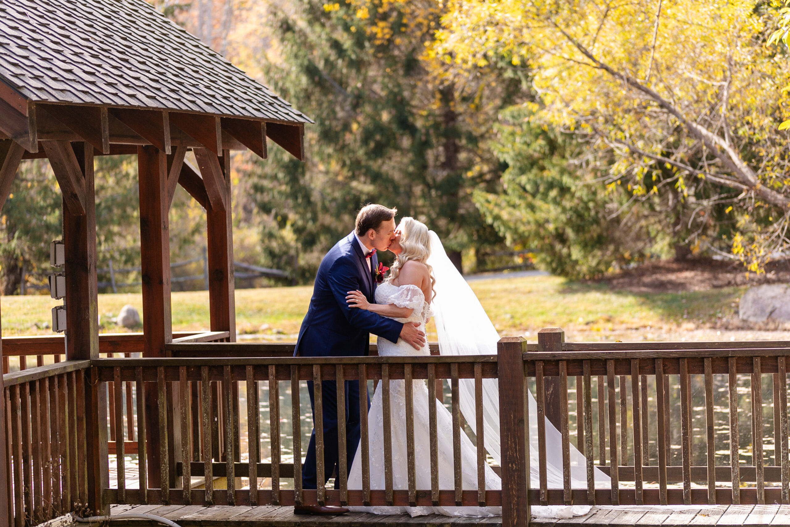 groom and bride kissing on a wooden bridge 