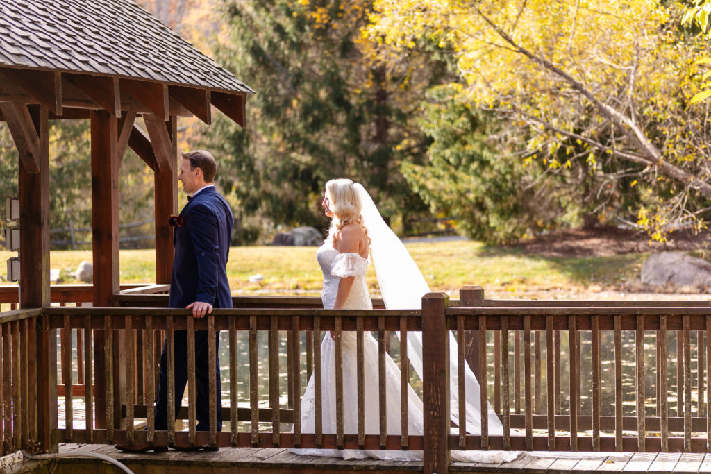 bride behind the groom on a bridge walking towards him