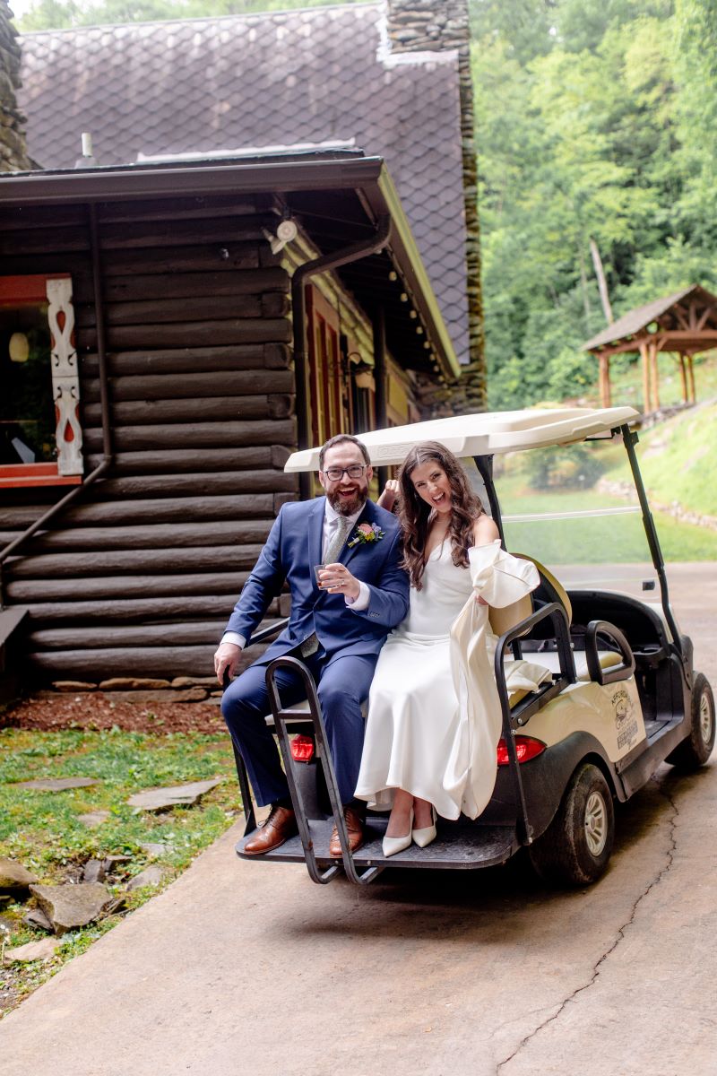 a man in a blue suit and woman in a white wedding dress sitting on a golf cart