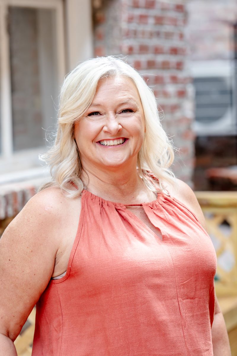 A woman in an orange dress posing for a headshot