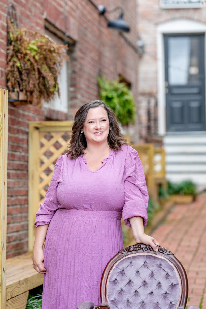 A woman in a purple dress posing for a headshot