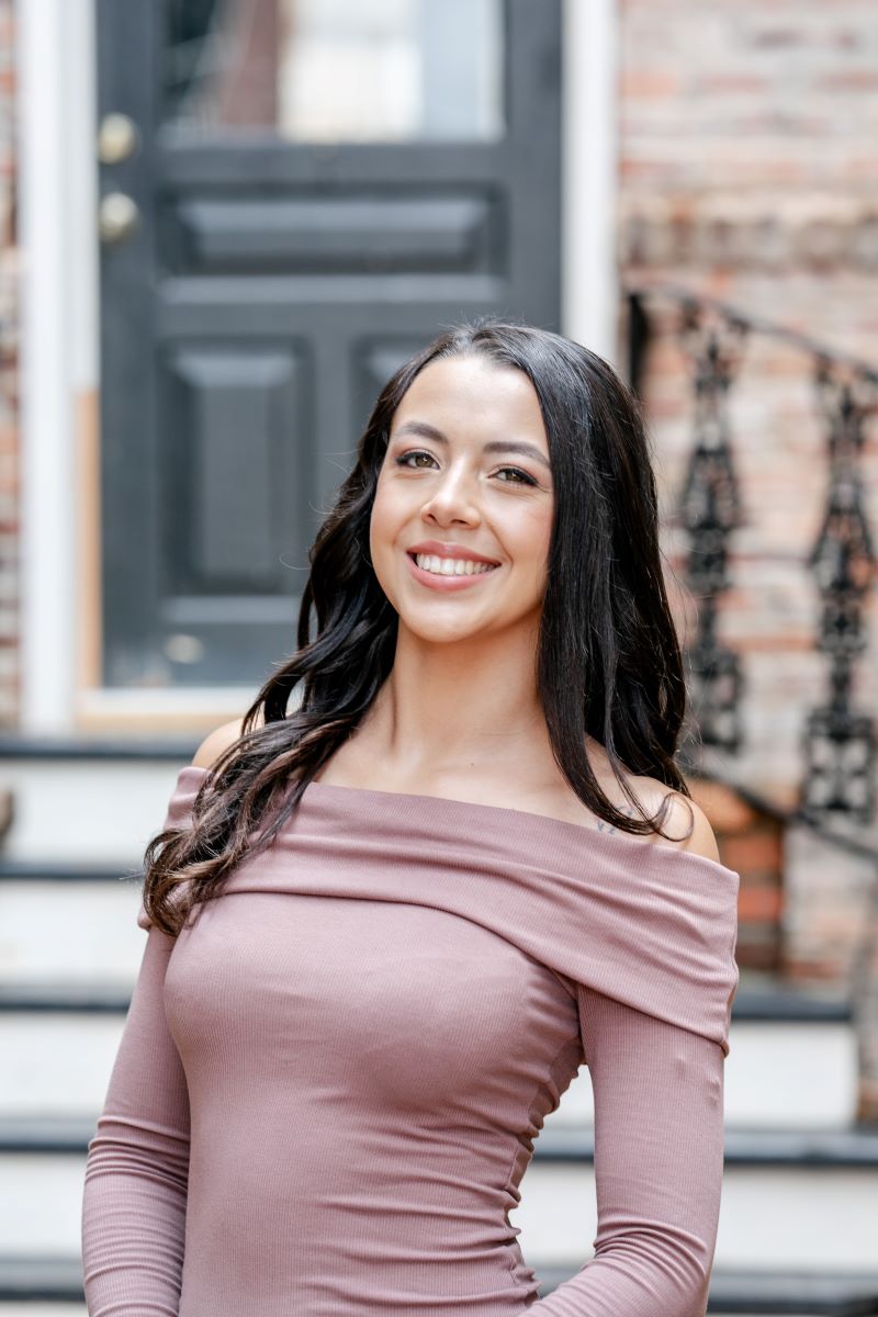 A woman in a brown dress posing for a headshot