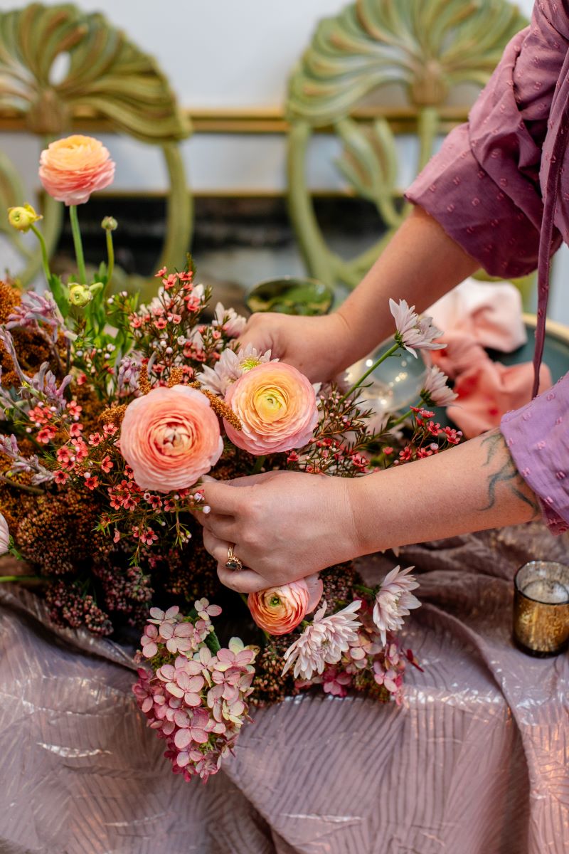 A woman arranging a bouquet of flowers on a table 