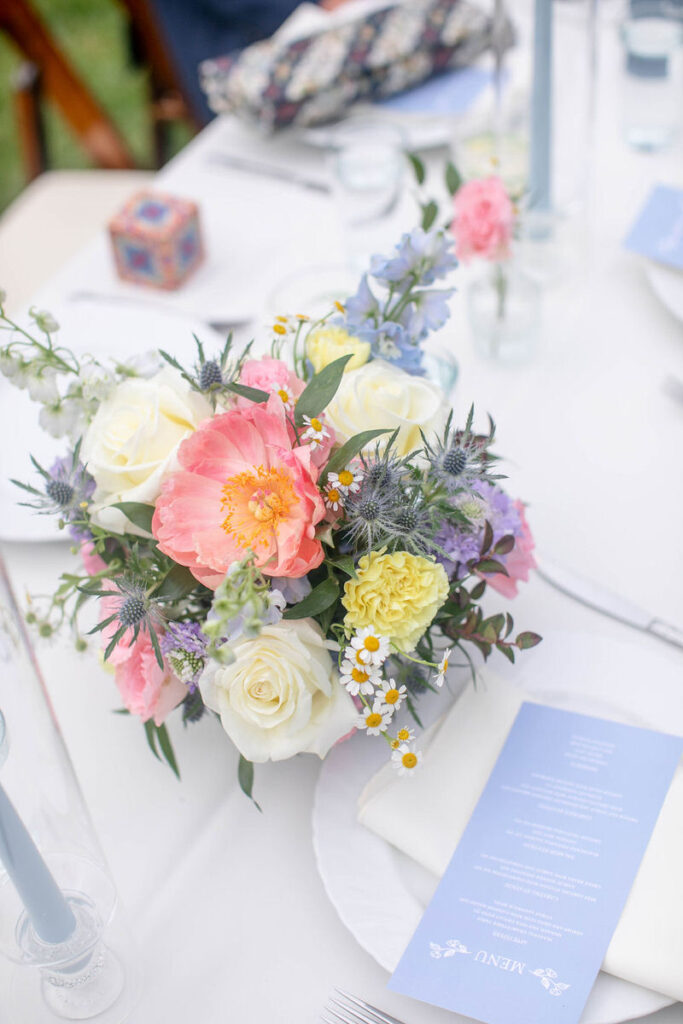 A flower bouquet on a wedding reception table with a small plate and card next to it. 
