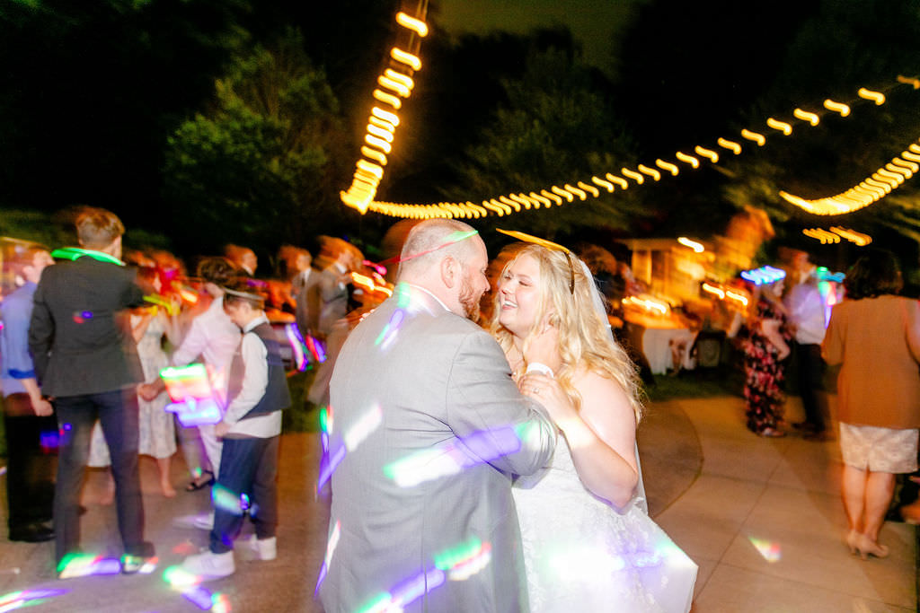 Lights dancing around an image of a newlywed couple dancing at their outdoor reception. 