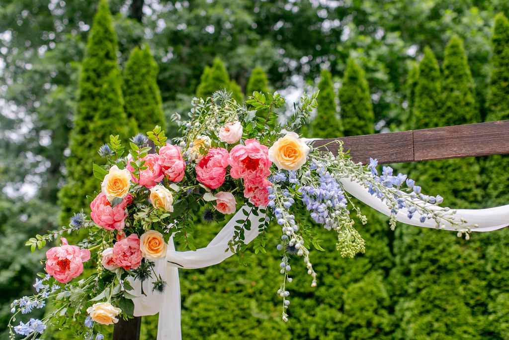 A colorful floral bouquet on the corner of a wedding arch. 