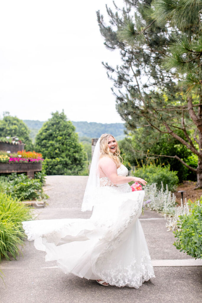 A person in a wedding dress smiling and spinning around in a garden. 