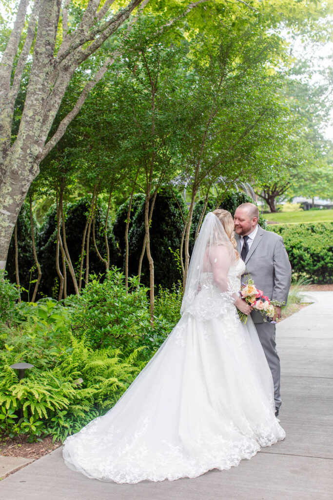 A newlywed couple about to kiss in a garden. 