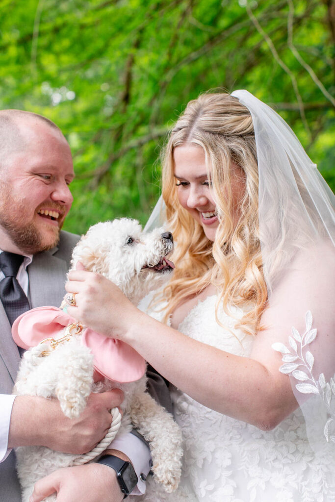 A wedding couple smiling with a dog in their arms 