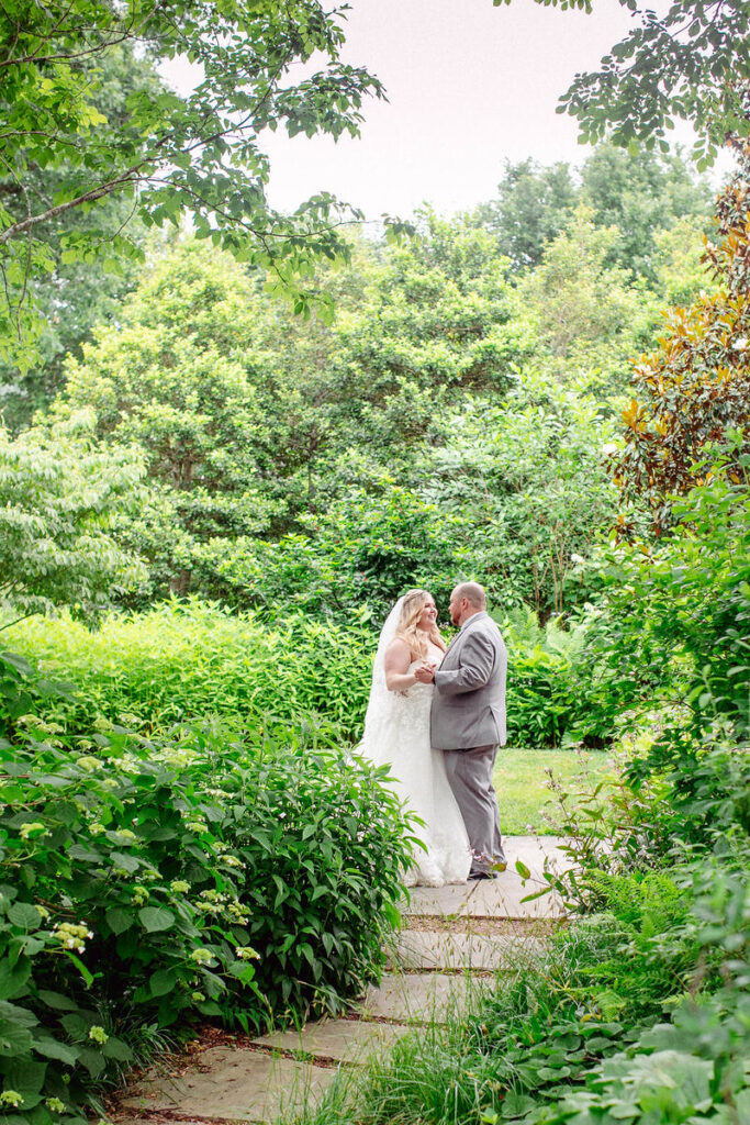 A newlywed couple dancing in a small garden 
