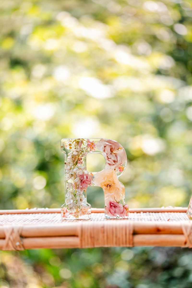 a glass letter R with preserved flowers inside 