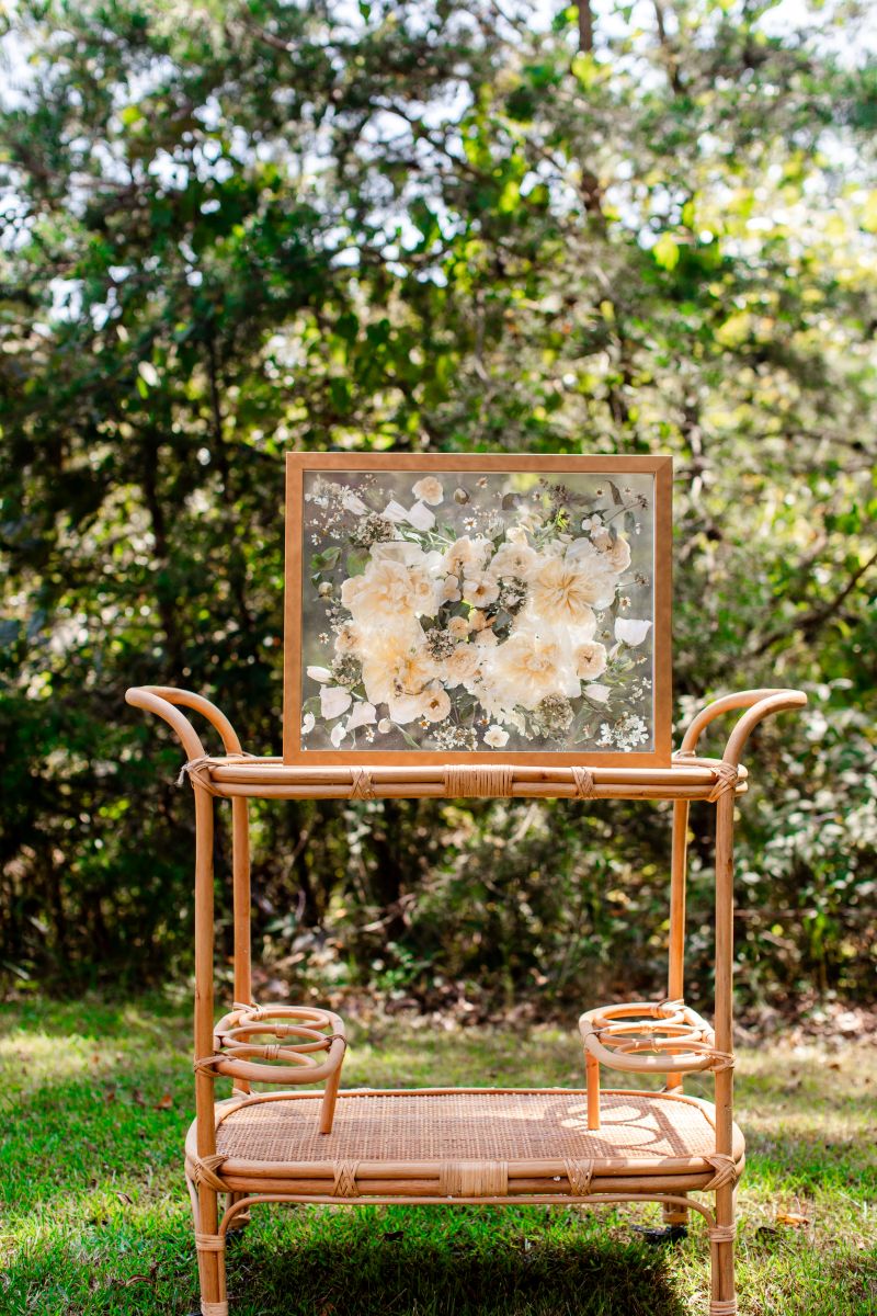 a wooden frame with flowers preserved inside on top of a wooden cart