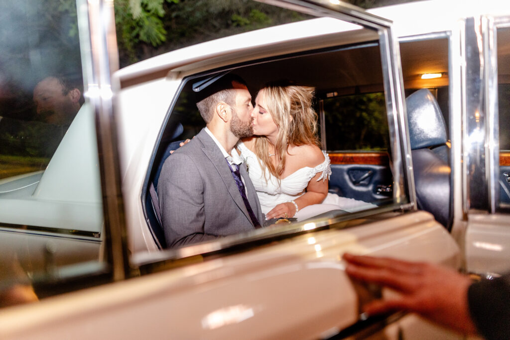 Bride and groom kissing in the back of a vintage car after their Homewood wedding in Asheville, photographed at night
