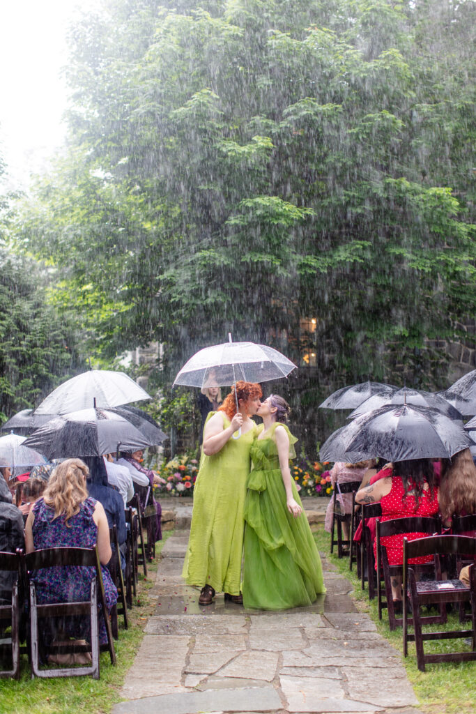 wedding couple walking down the aisle with umbrellas during a rainy outdoor wedding ceremony in Asheville NC