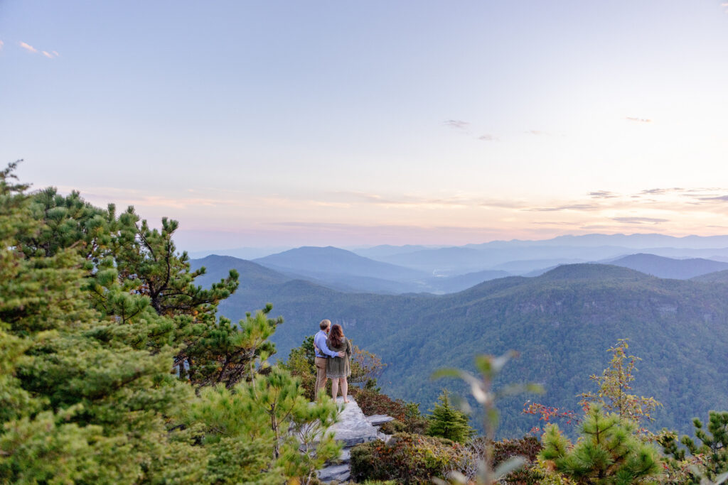 couple standing on a mountain overlook at sunset during their engagement session in the Blue Ridge Mountains near Asheville NC
