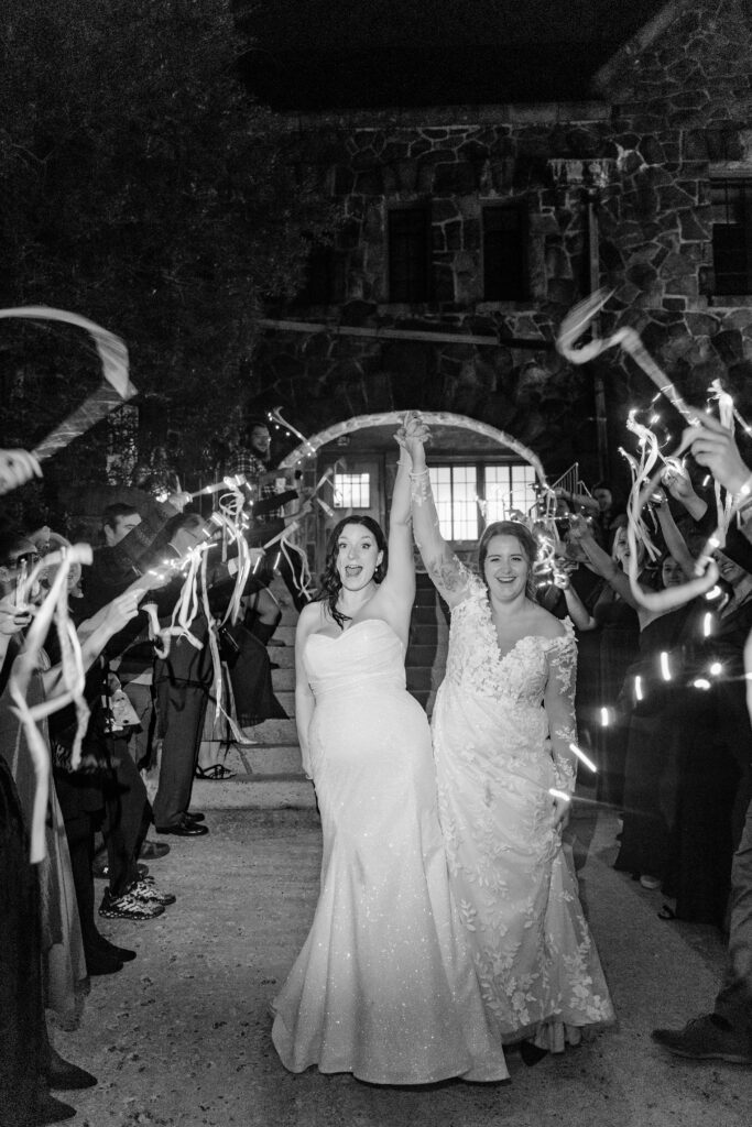 black and white photo of two brides celebrating their ribbon wand exit at an Asheville NC wedding
