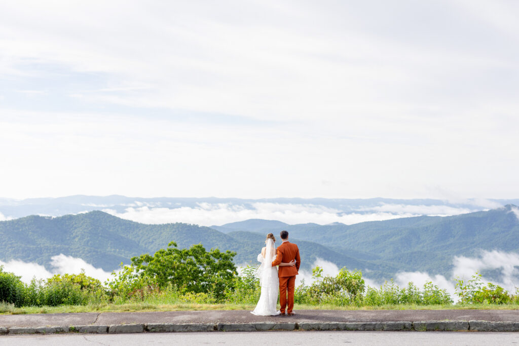 bride and groom overlooking the Blue Ridge Mountains from the Blue Ridge Parkway on their wedding day in Asheville NC