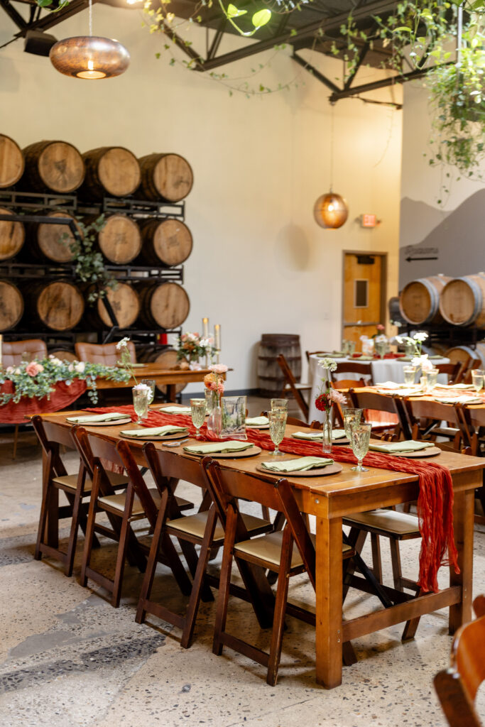 farm table wedding reception tablescape with rust runner and floral centerpieces in the Barrel Room at Highland Brewing Company in Asheville NC