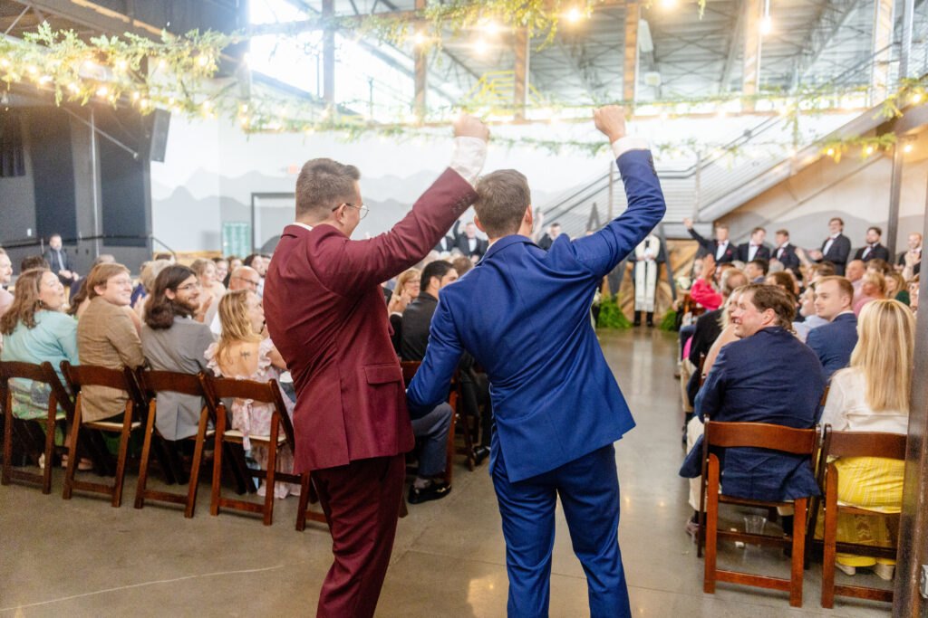 two grooms dancing with hands raised during wedding reception at Highland Brewing Company in Asheville NC