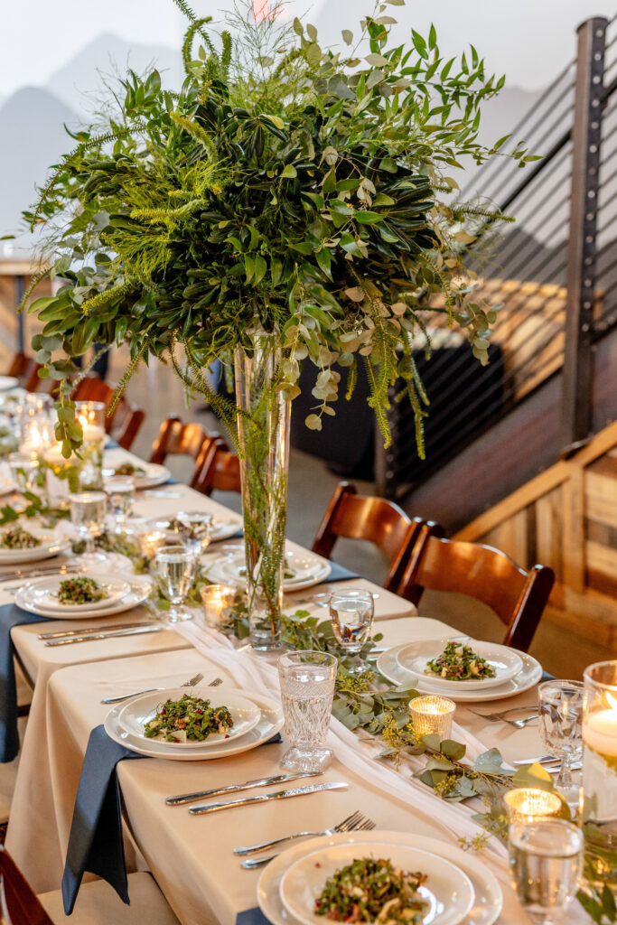 wedding reception tablescape with tall greenery centerpiece and candlelight at Highland Brewing Company Event Center in Asheville NC