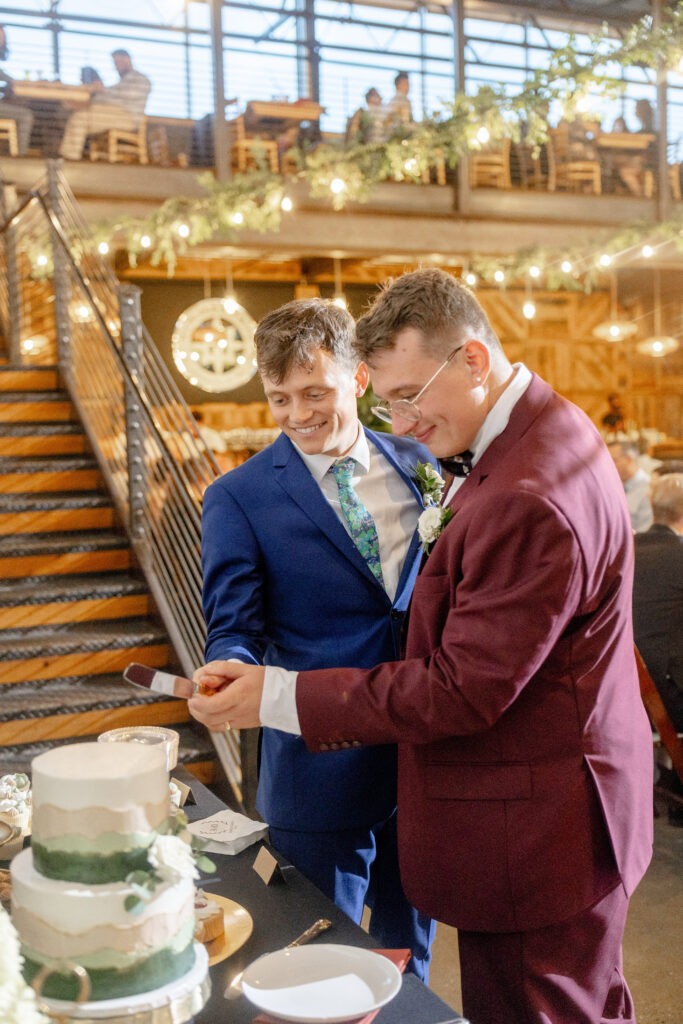 two grooms cutting wedding cake at Highland Brewing Company reception in Asheville NC