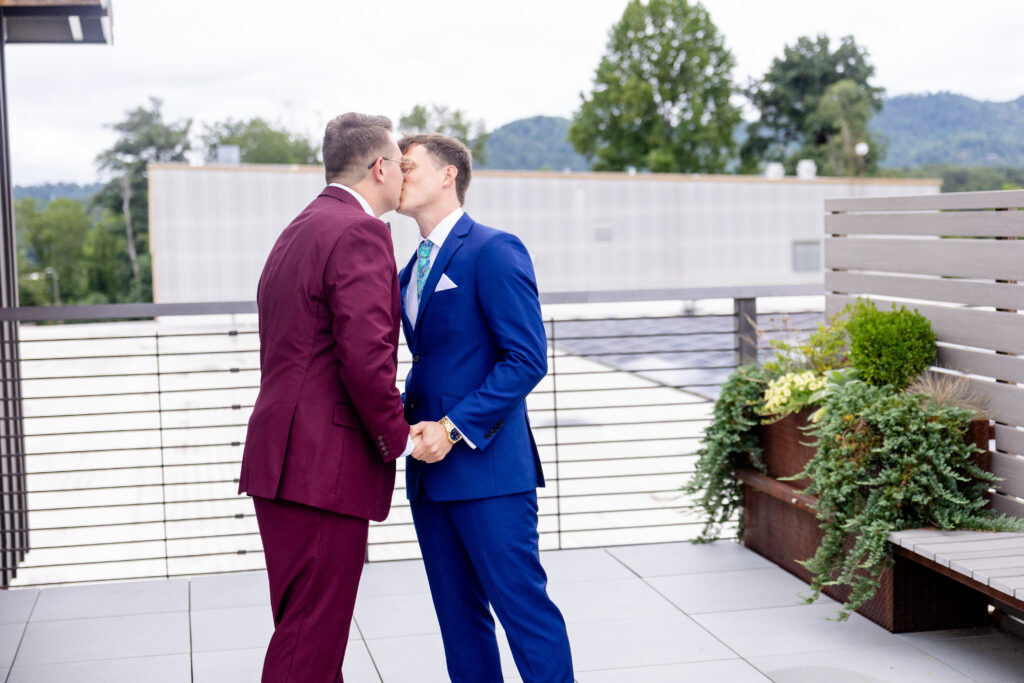 two grooms share a first look kiss on the rooftop at Highland Brewing Company in Asheville NC