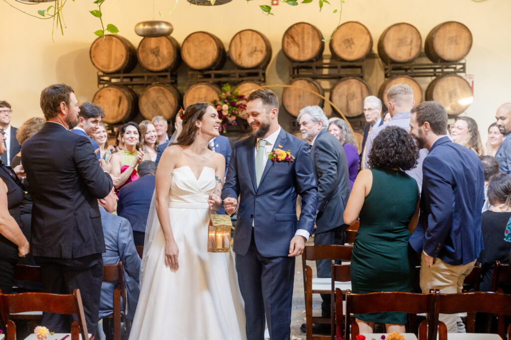 bride and groom walking back down the aisle after their wedding ceremony in the Barrel Room at Highland Brewing Company in Asheville NC surrounded by cheering guests