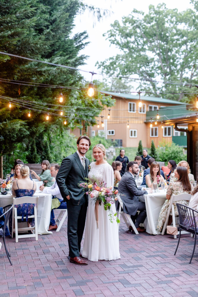 bride and groom smiling at their outdoor garden wedding reception with string lights in Asheville NC
